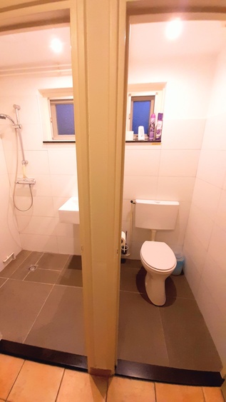 Badezimmer mit Dusche, Waschbecken, und WC