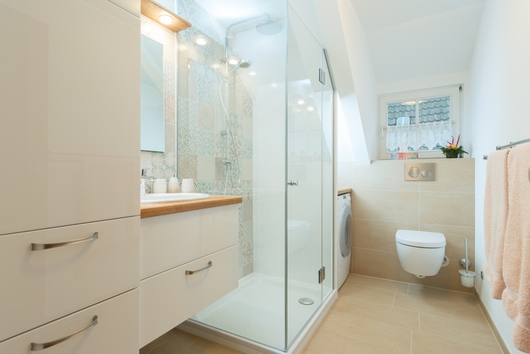 Badezimmer mit Waschbecken, großer Dusche, Waschmaschine und WC