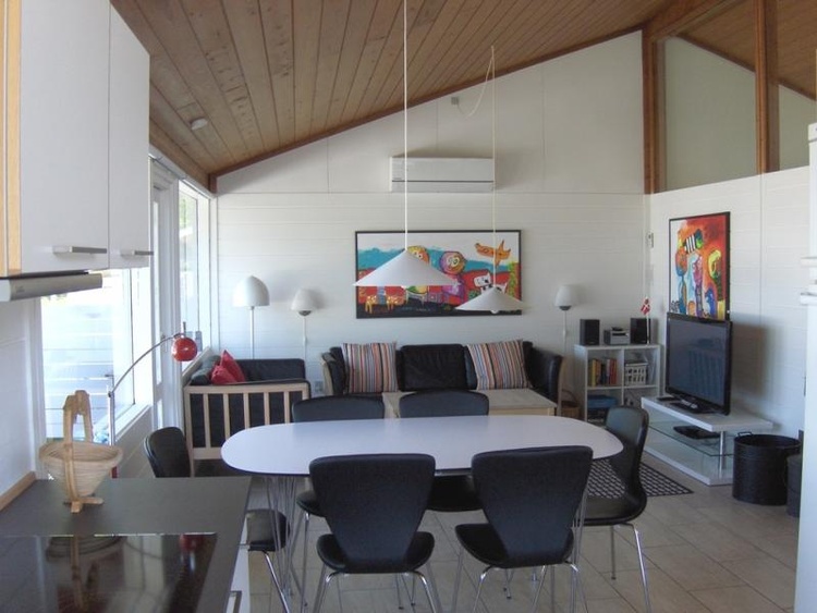 Offener Zugang zwischen Wohnzimmer und Küche. Die großen Fenster sorgen für viel Licht. Holzofen