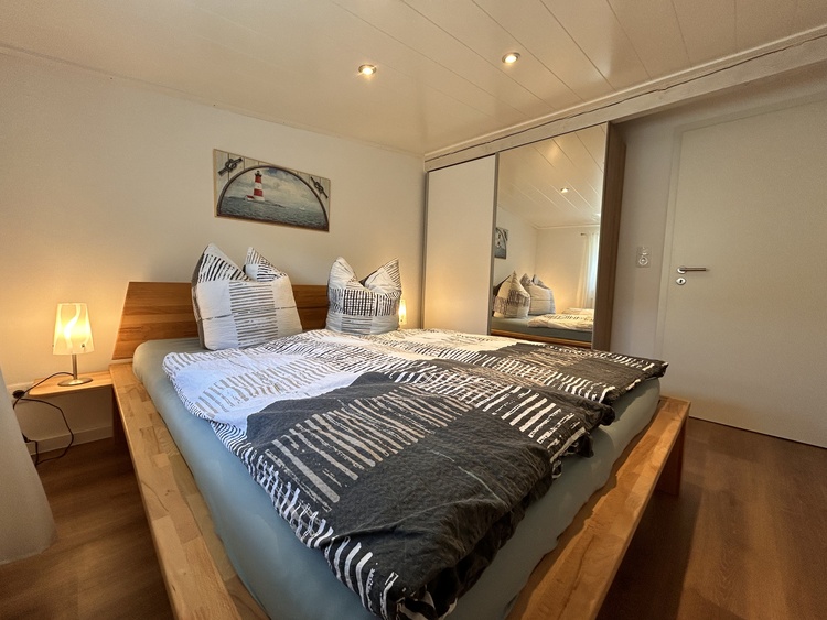 Schlafzimmer 1, mit Bett und Schiebetürenschrank mit Spiegel