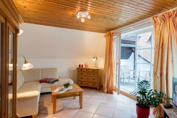 Wohnzimmer mit Sitzcouch, TV und Zugang zur Balkonterrasse