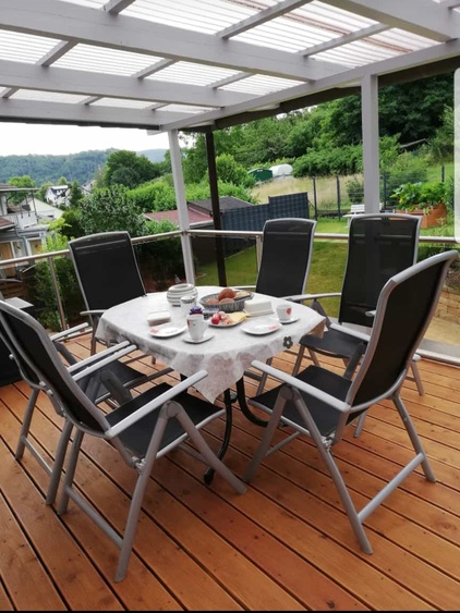 Überdachter Balkon mit Blick über Wiesen bis zum Wald.